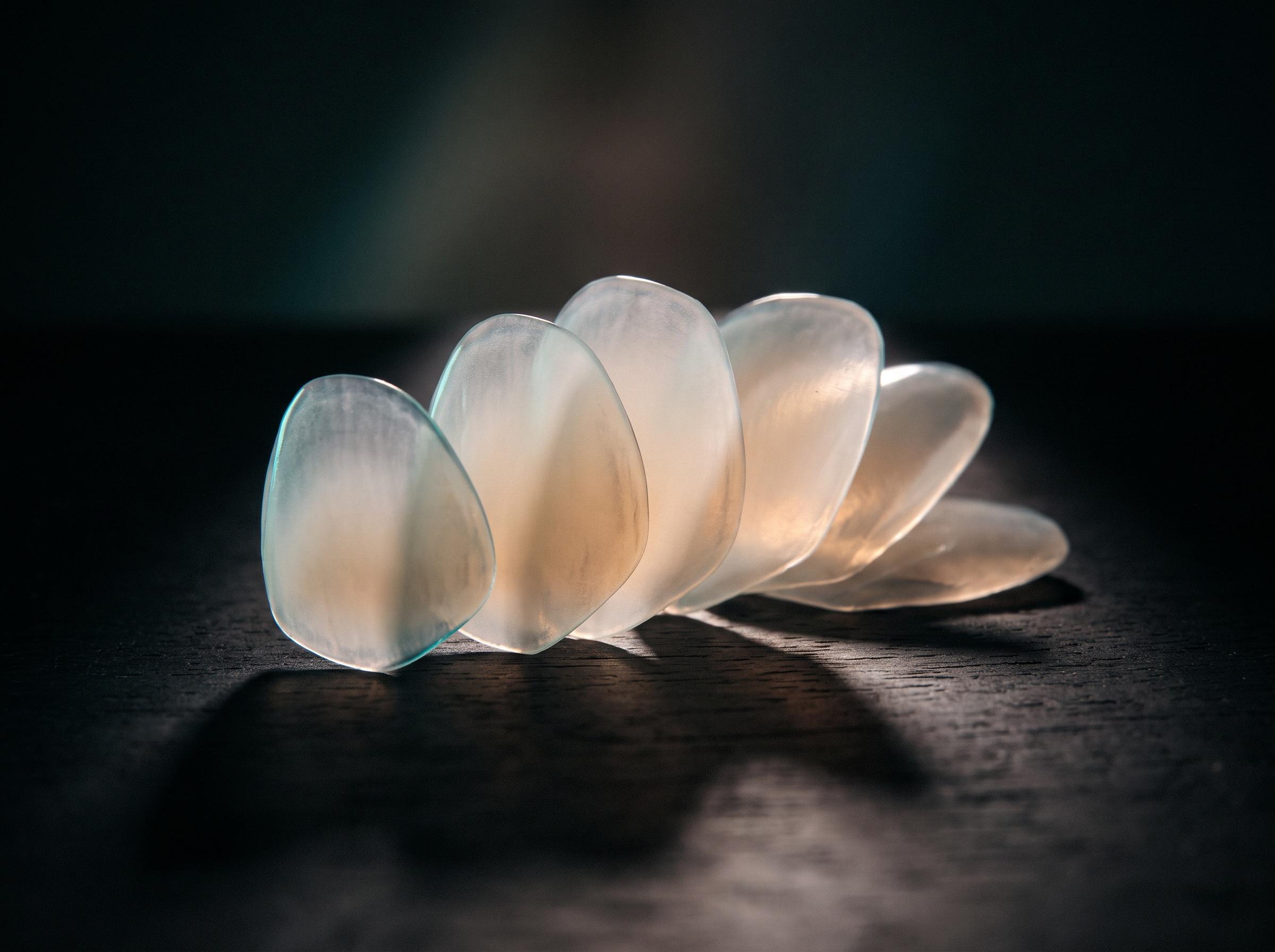 Carillas de porcelana translúcidas dispuestas en abanico sobre una superficie oscura